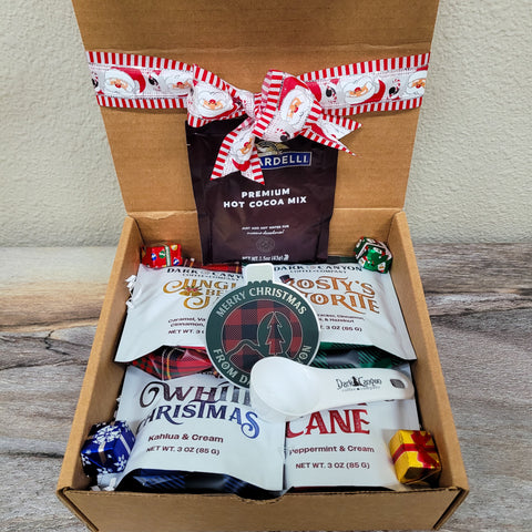 Box of Christmas-themed snacks and hot cocoa mix with a decorative ribbon.