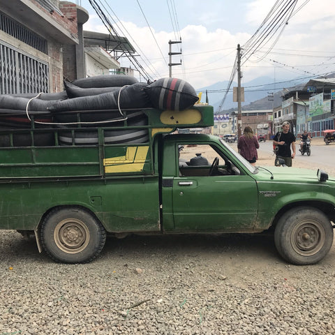 Green pickup truck with coffee bags on a street in an urban area