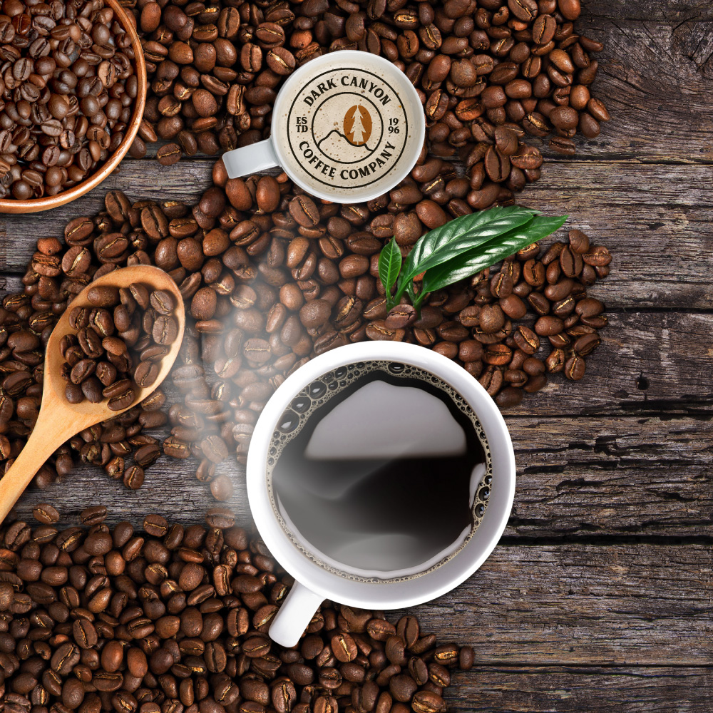 coffee beans scoop on wood background with coffee mugs and leaf dark canyon coffee circle logo